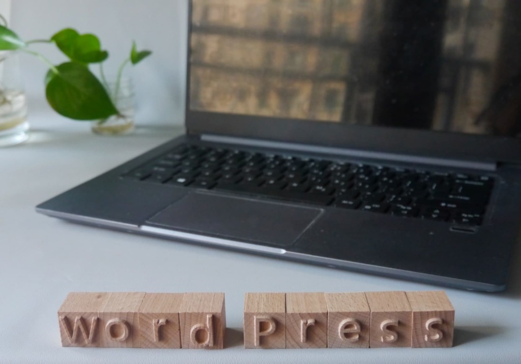 wordpressのイメージ画像。ノートパソコンの前にwordpressと書かれたオブジェが置かれている。