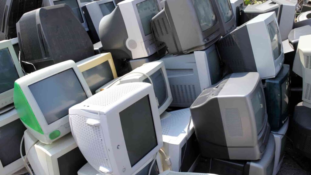 古いパソコンやディスプレイが並べられた廃棄物置き場の写真。