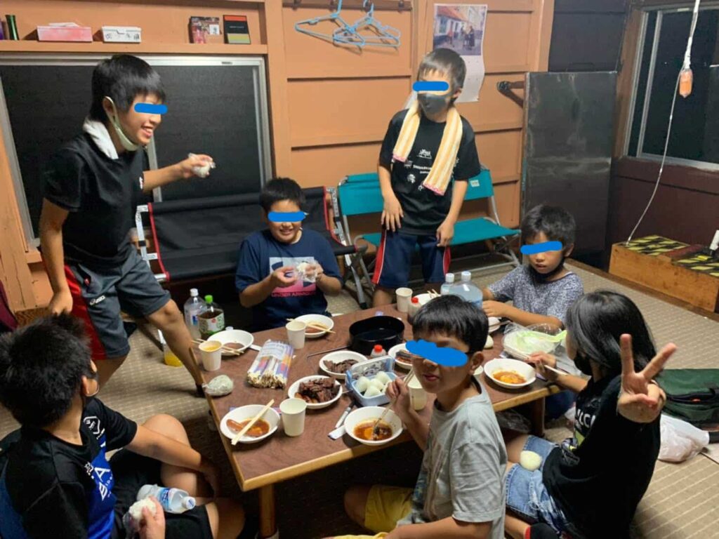 7人の子供たちが集まってご飯を食べている写真。